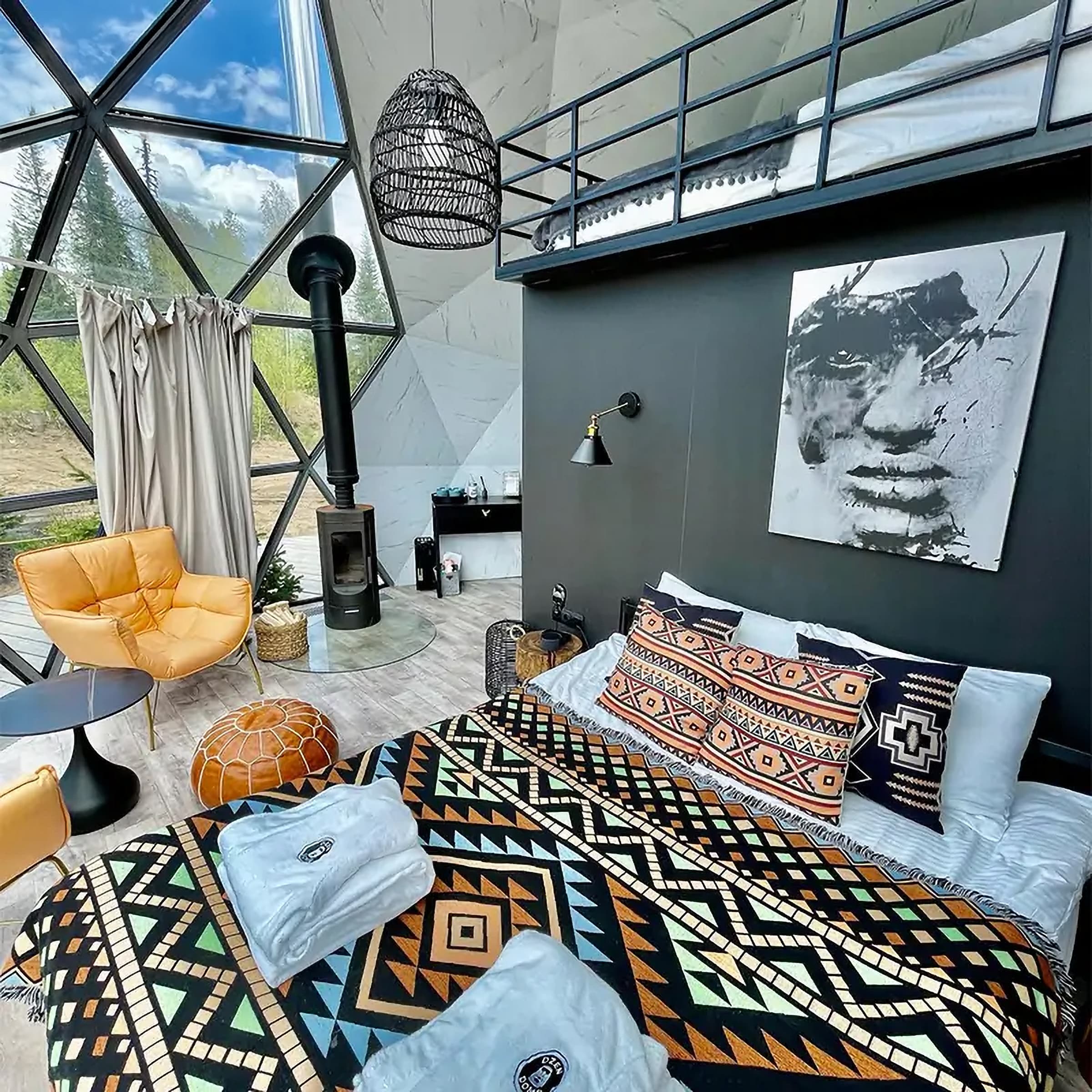 Inside a glass geodesic dome: a bed, a wood stove and a loft