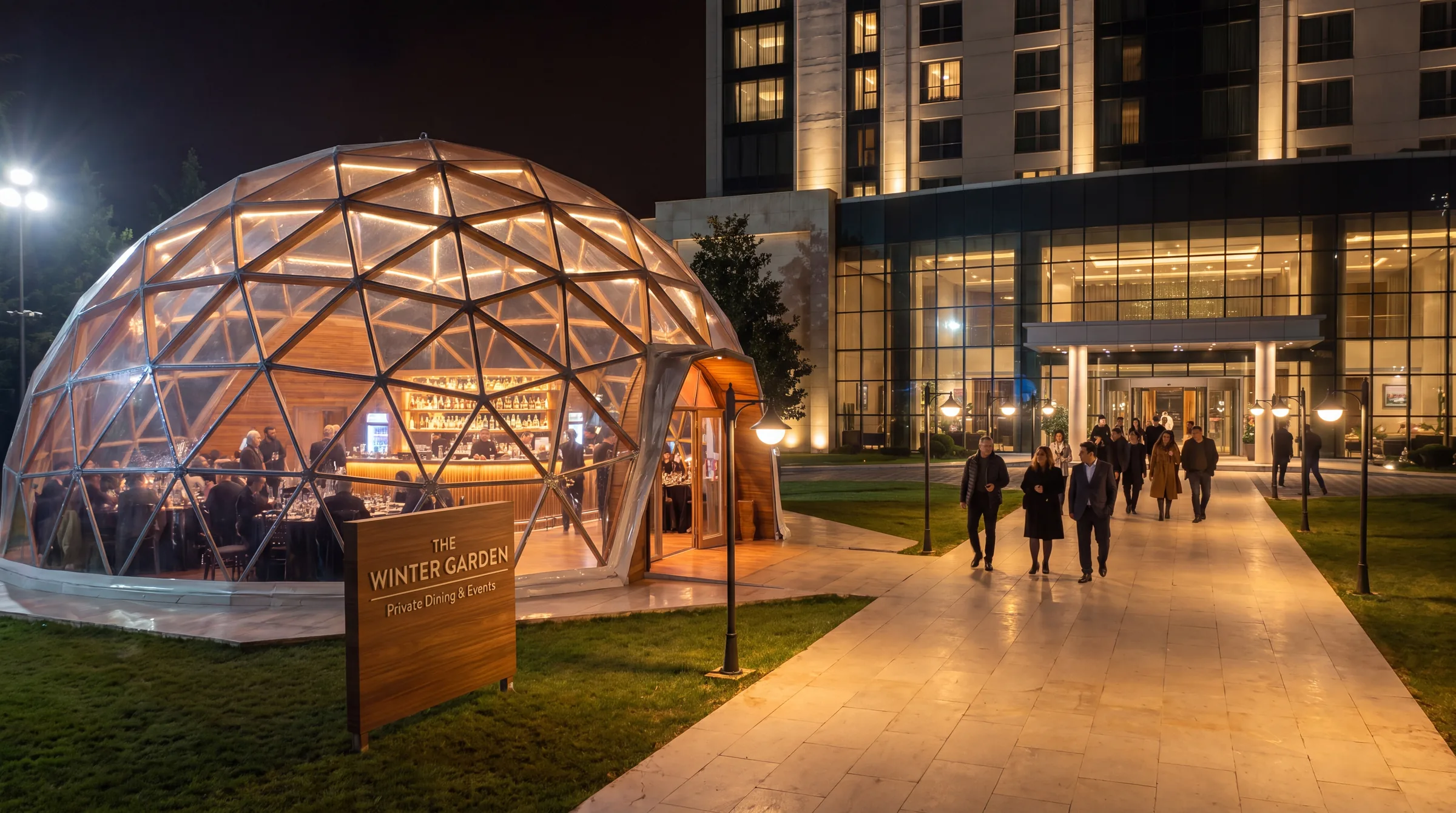 Geodesic dome lit up as a dining and events venue beside a hotel in the evening