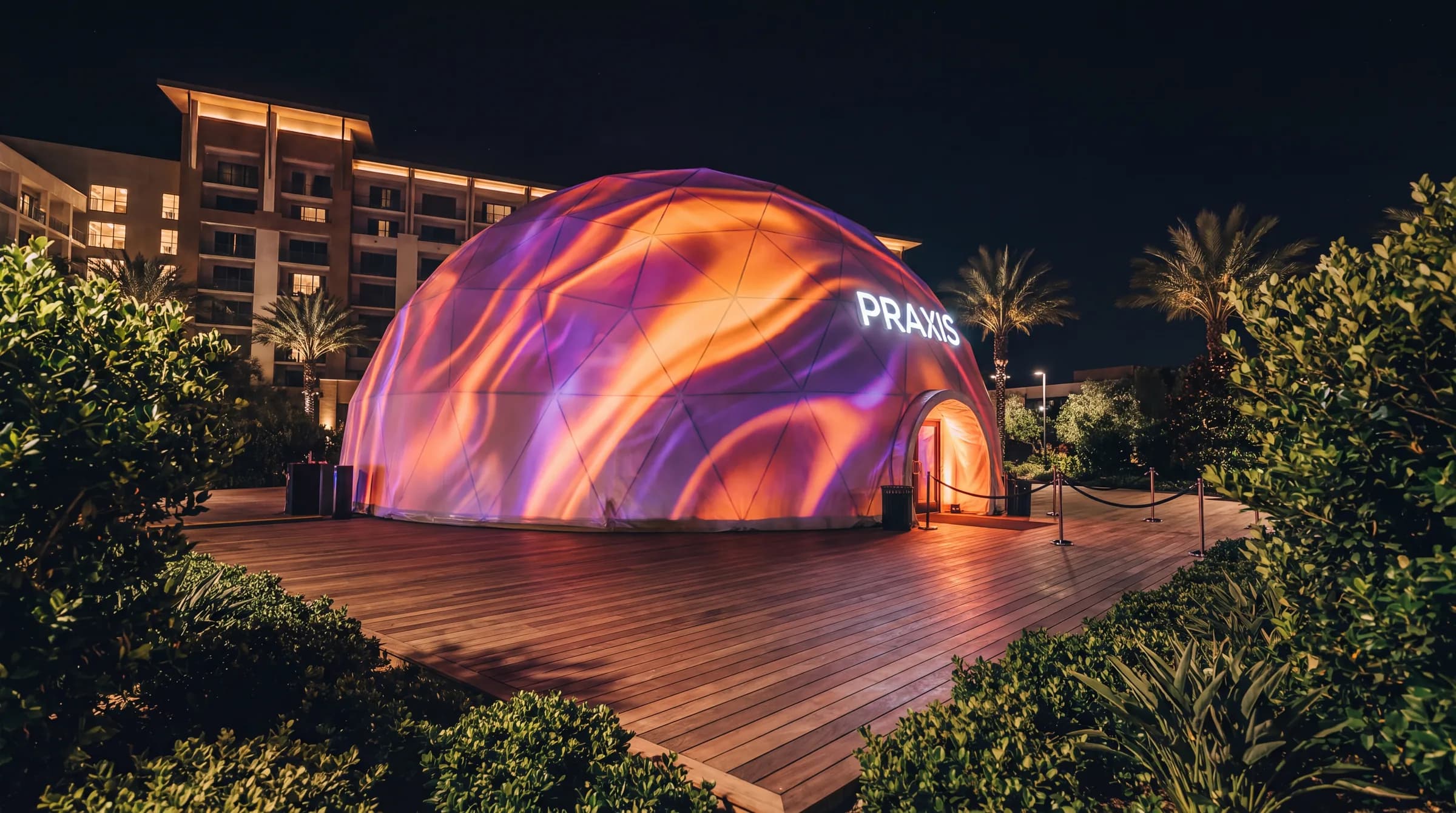 Projection dome illuminated at night with visuals across its exterior